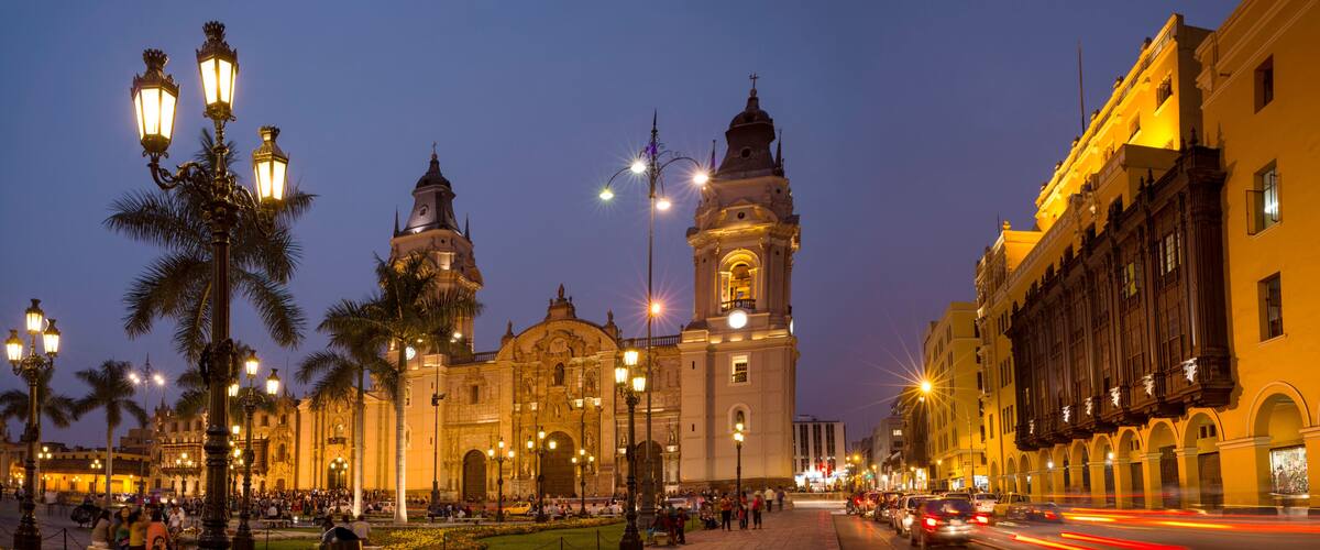 A historic building with a clock tower, surrounded by palm trees and street lamps.