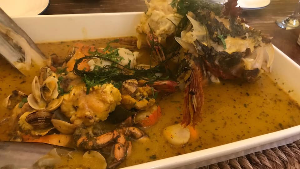 Ein Fischgericht mit Muscheln, Garnelen und Krabbenbeinen in einer weißen Schüssel.