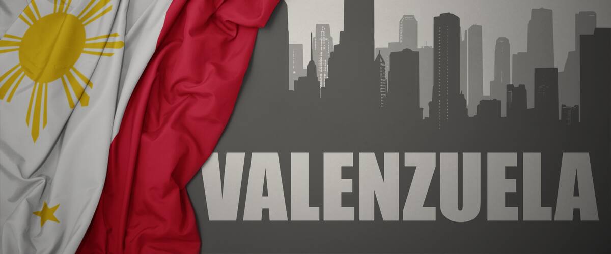 abstract silhouette of the city with text Valenzuela near waving national flag of philippines on a gray background.3D illustration