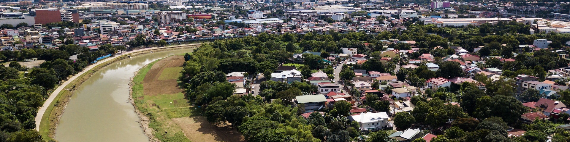 Un río serpentea por una ciudad con un horizonte urbano denso al fondo.