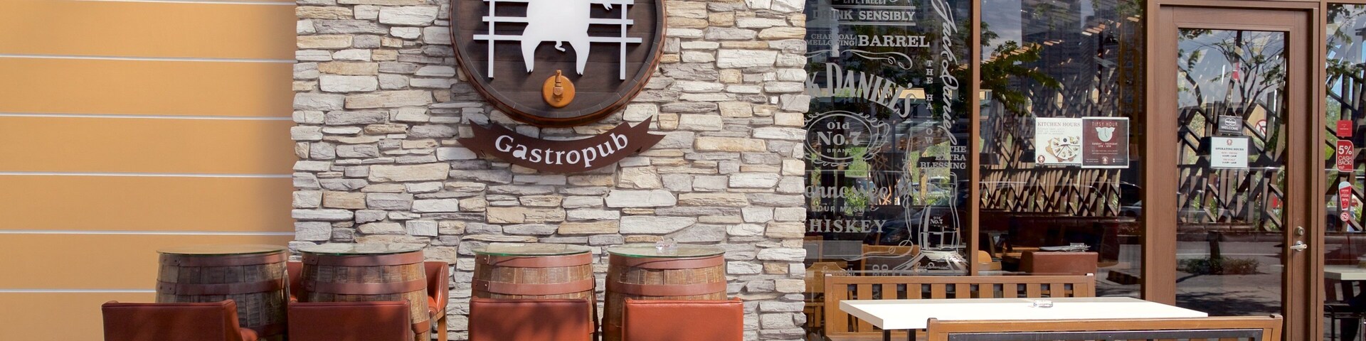 Un gastropub con pared de piedra y barriles de madera como asientos.