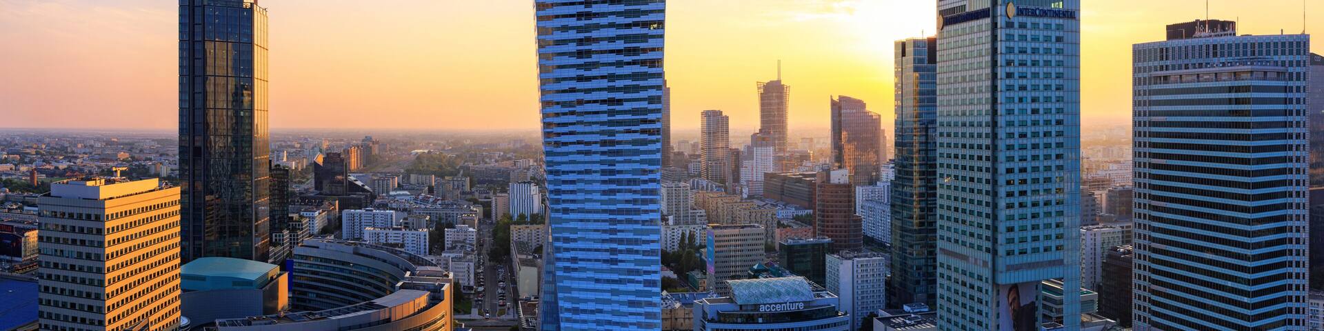 A cityscape with tall skyscrapers and a sunset.