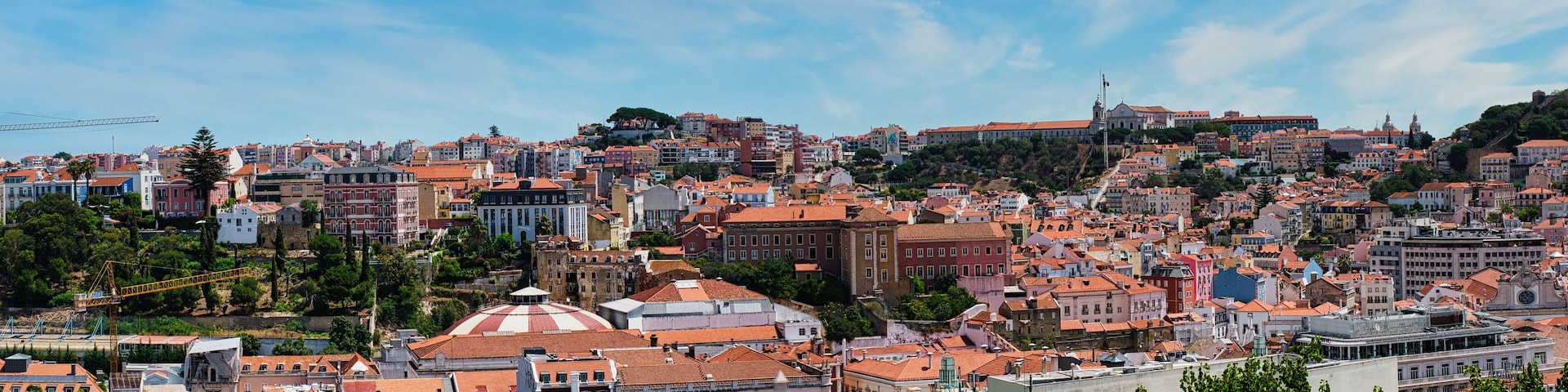 A densely packed cityscape with historic buildings and a prominent hill with a church.