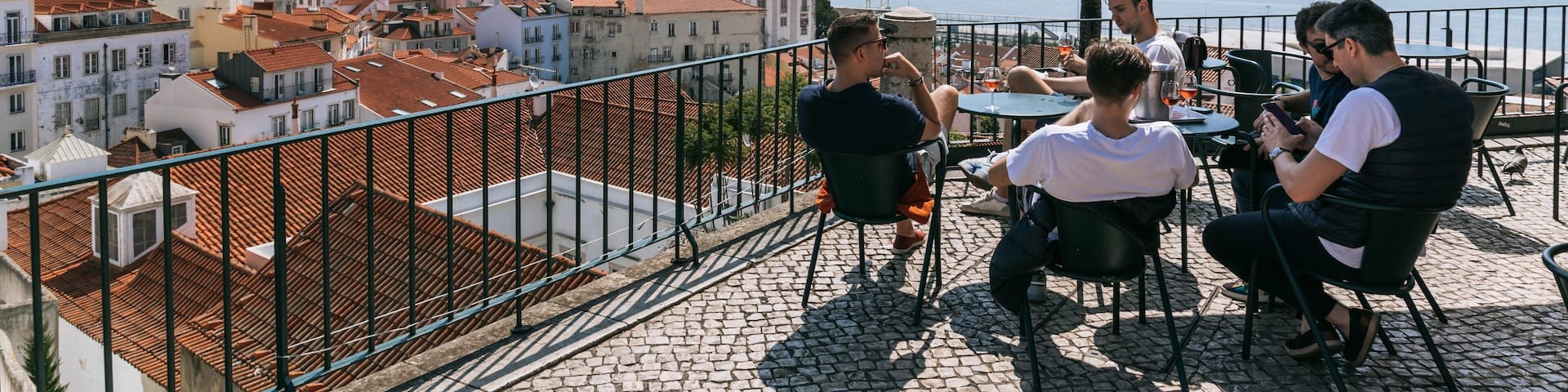 Alfama showing a coastal town and a sunset as well as a small group of people