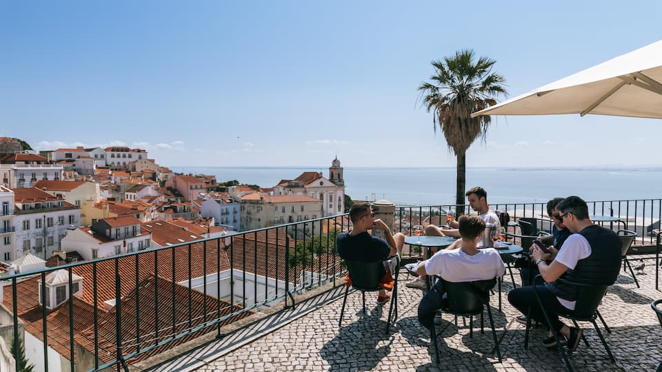 Alfama showing a coastal town and a sunset as well as a small group of people