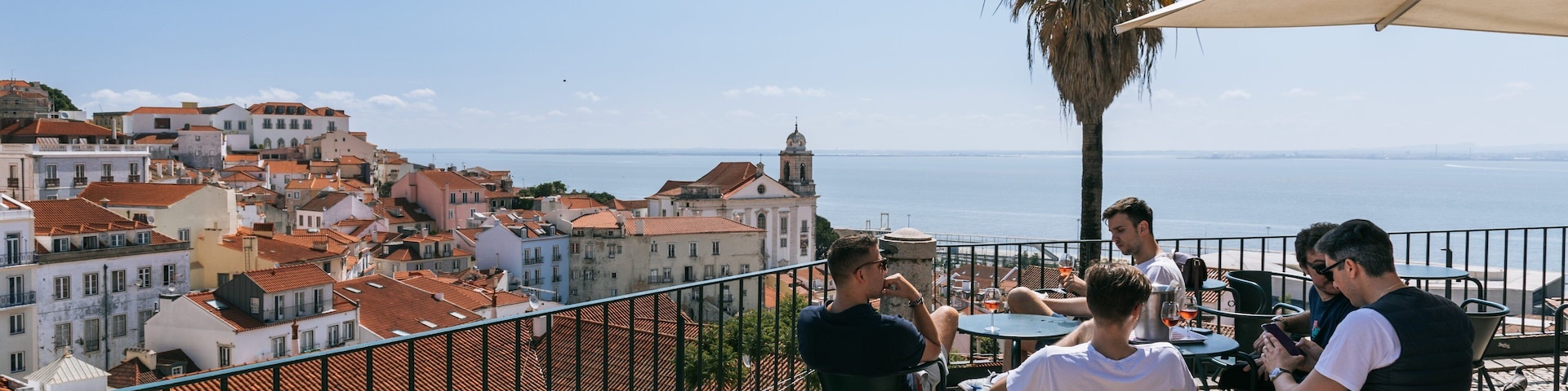 Alfama showing a coastal town and a sunset as well as a small group of people