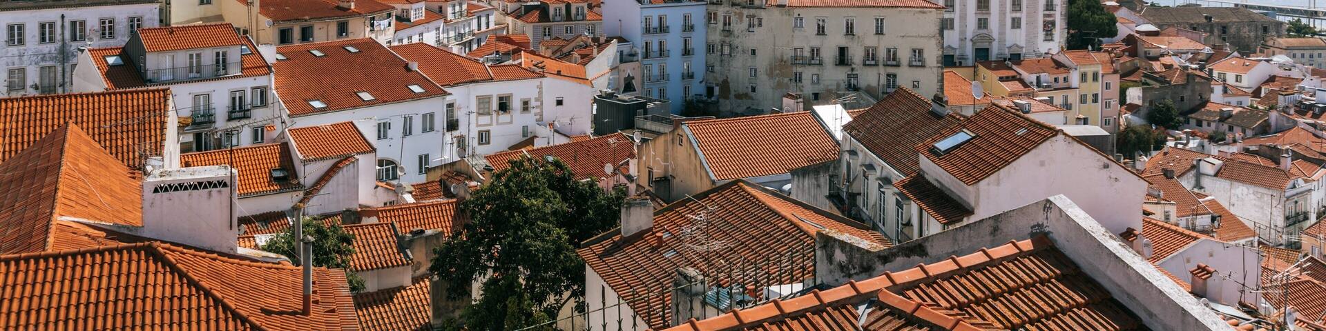 A coastal town with terracotta-roofed buildings, a prominent church with a dome, and a sea view.