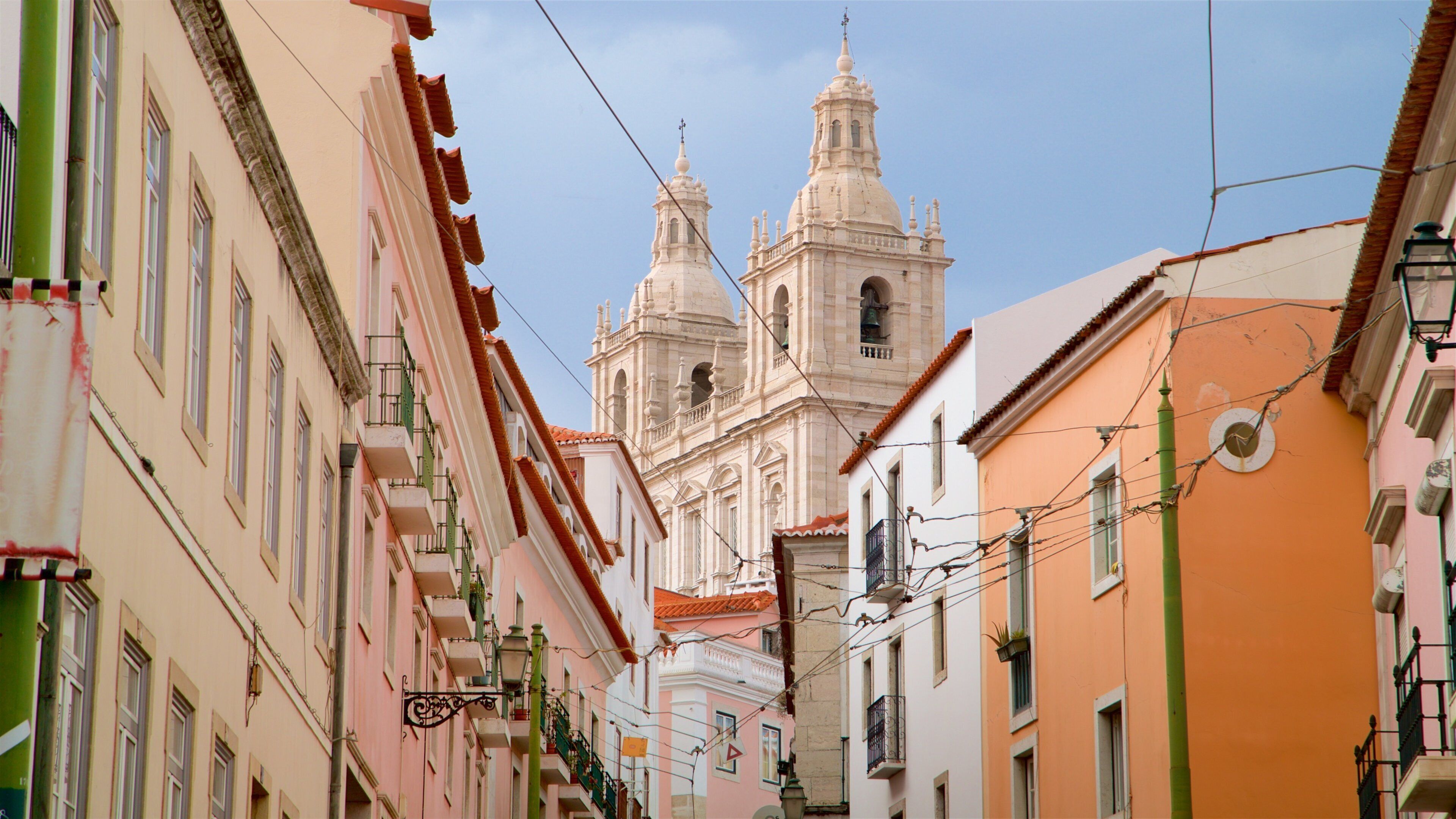 A narrow street with colorful buildings and a prominent church with two towers.