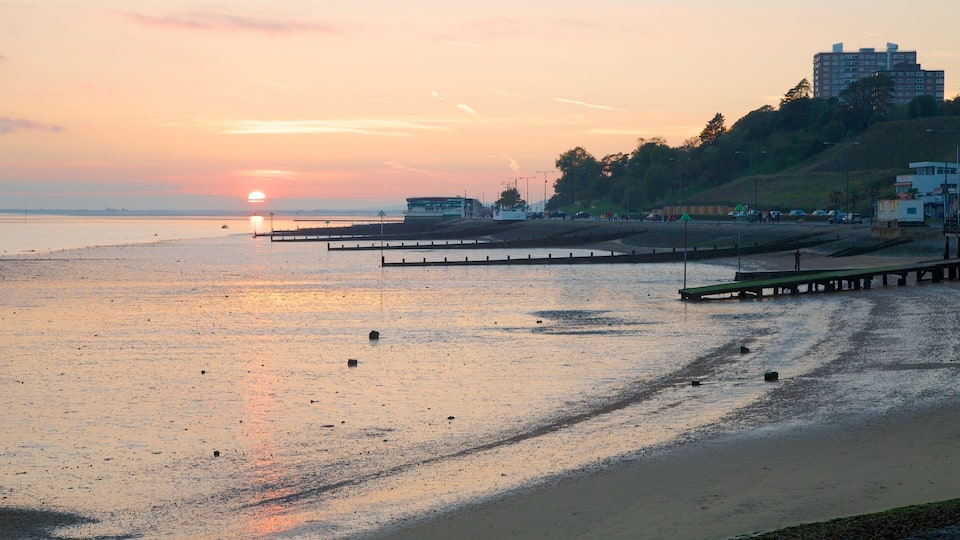 A sunset over a beach with a pier extending into the water.