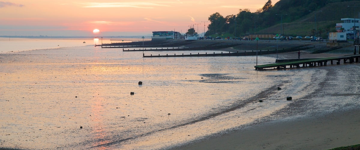 A sunset over a beach with a pier extending into the water.