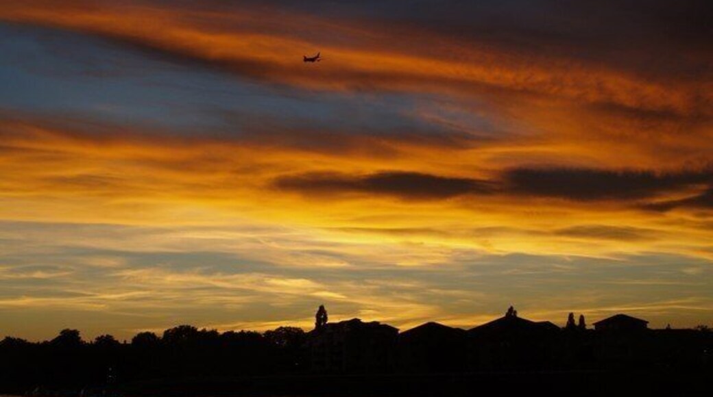 Sunset over Thames A jet on the run-in to Heathrow flies over Hurlingham and the roofs of buildings beside Petrofina Wharf. The sunset is seen across the river from close to the Solid Waste Transfer Station at Riverside West.