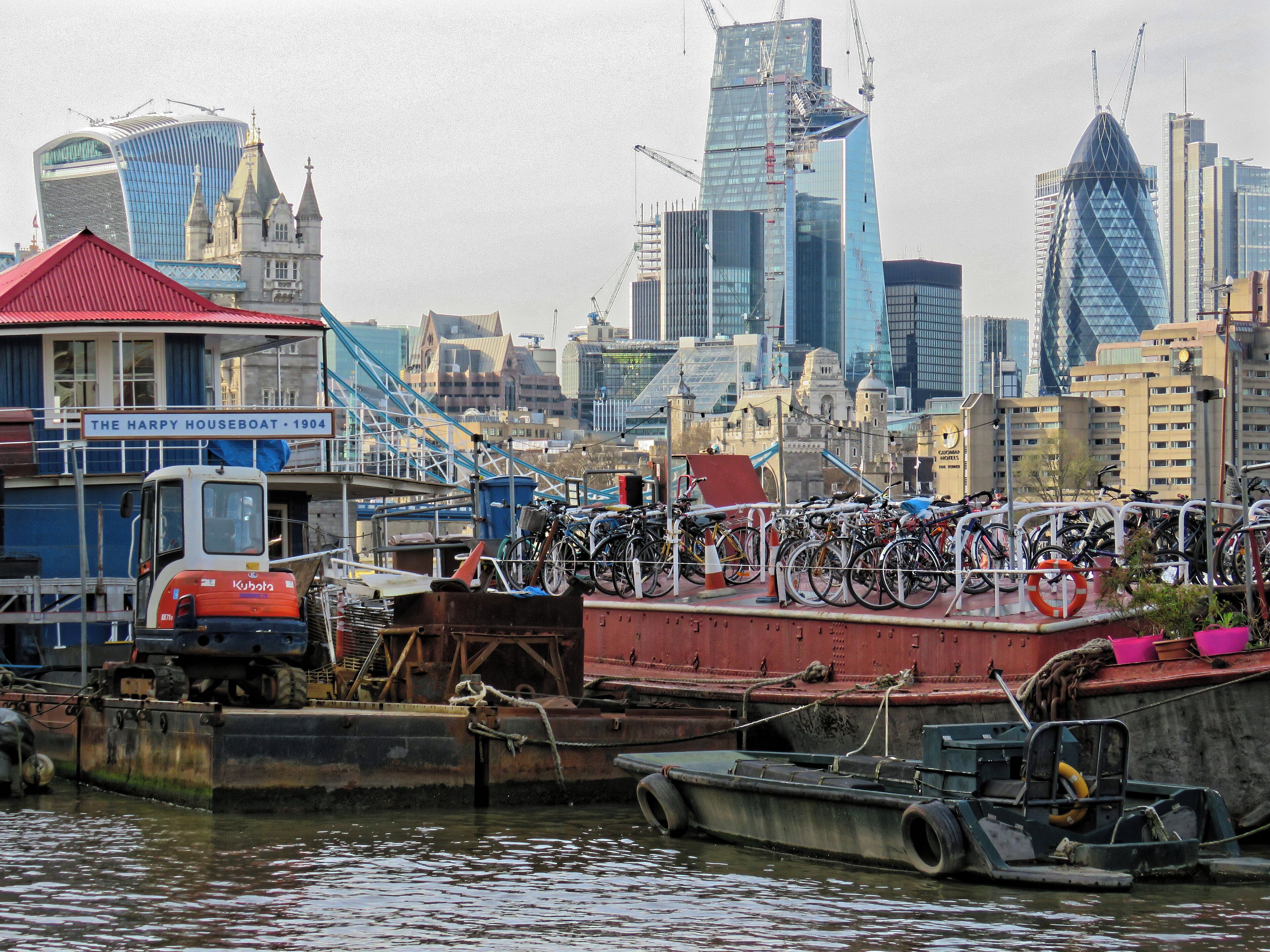 Boats moored off New Concordia Wharf looking northwest towards the City of London from the Thames Path in Bermondsey, Southwark, London, England. Camera: Canon PowerShot SX60 HS. Software: file lens-corrected and optimized with DxO PhotoLab Elite and Viewpoint 3, and further optimized with Adobe Photoshop CS2.