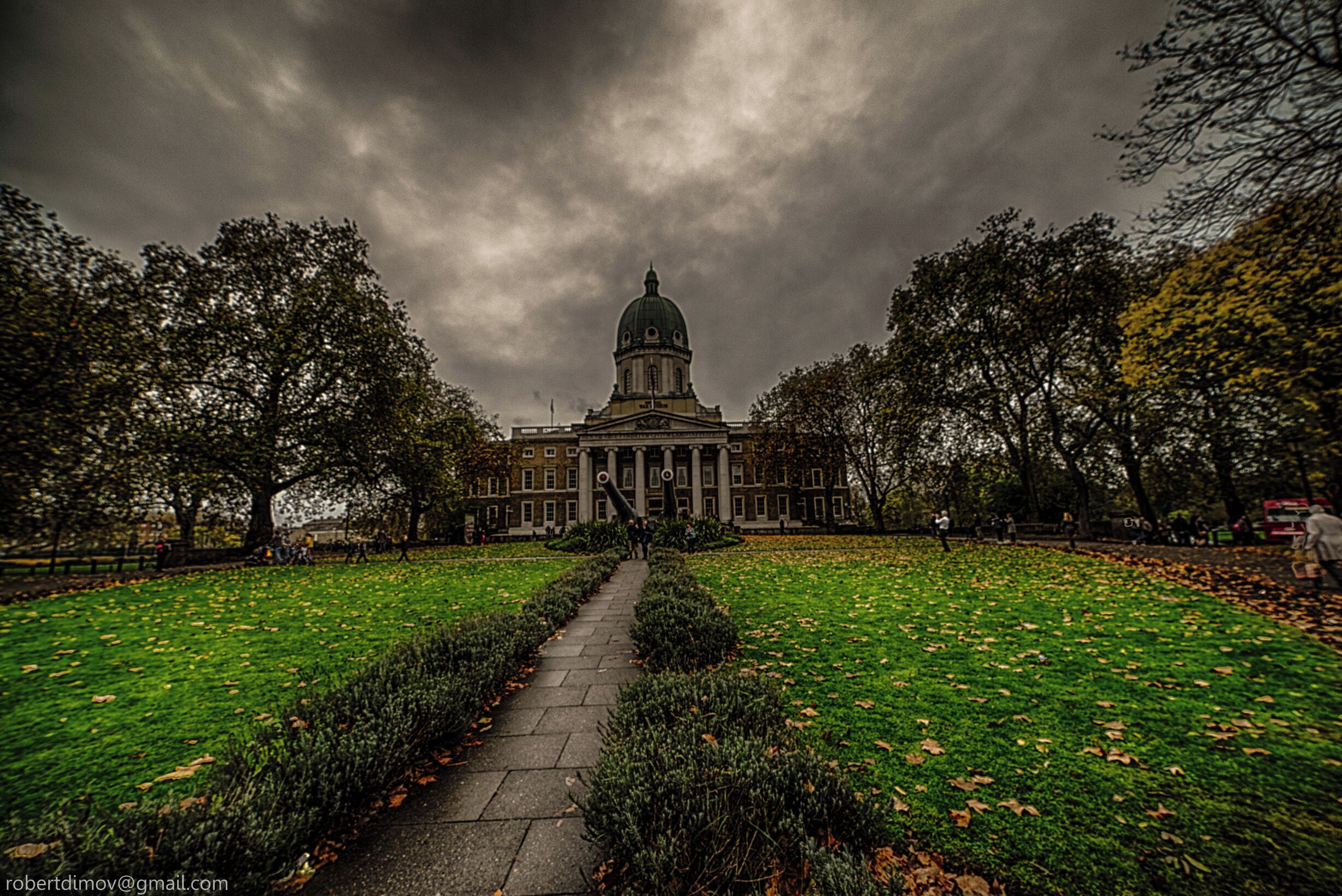 A grand building with a dome, surrounded by a well-maintained lawn and a pathway leading to it.