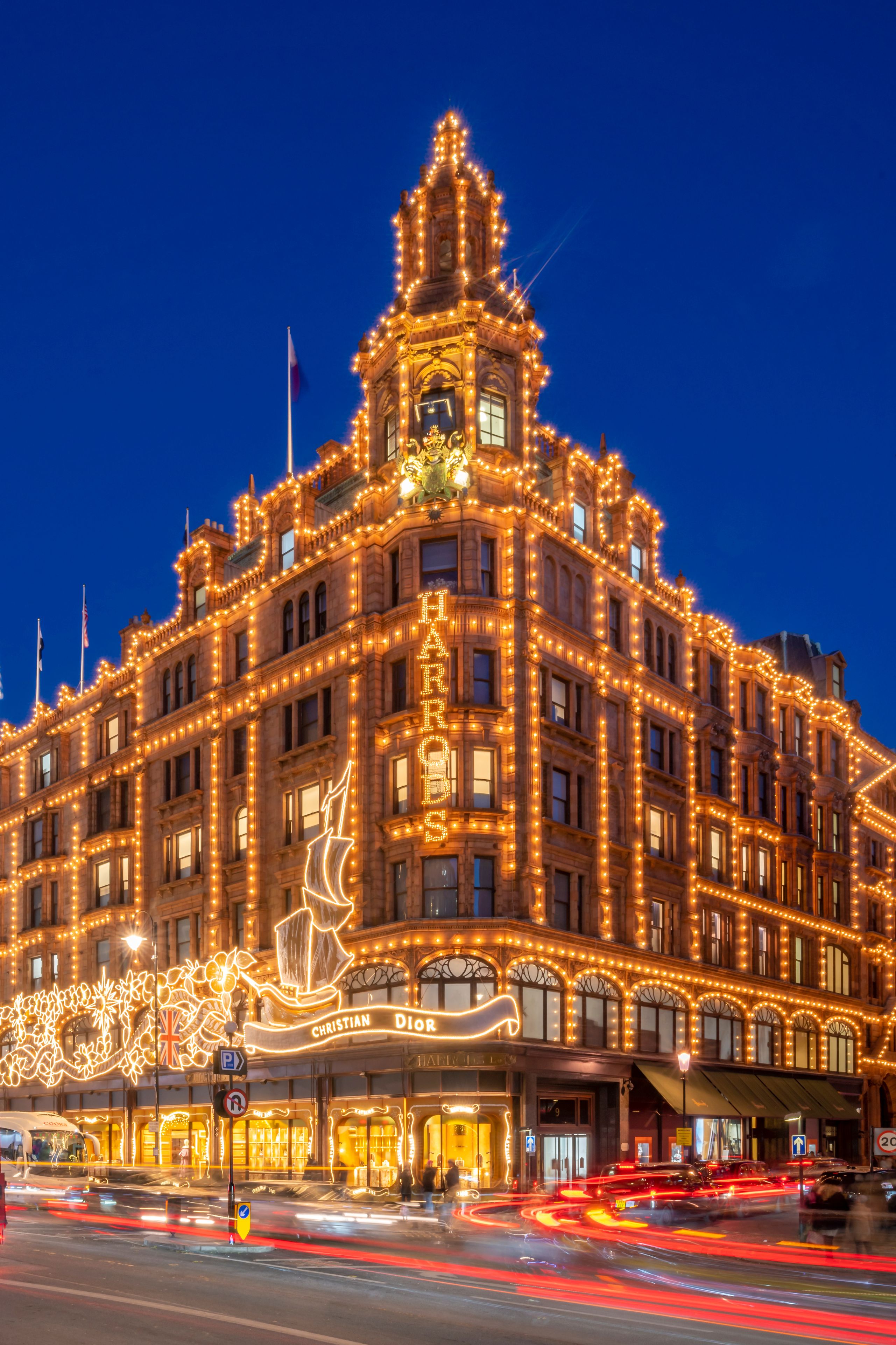 A grand, illuminated building with ornate architecture and a prominent sign reading 'CHRISTIAN DIOR.'