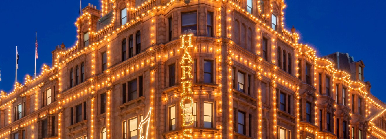 A grand, illuminated building with ornate architecture and a prominent sign reading 'CHRISTIAN DIOR.'