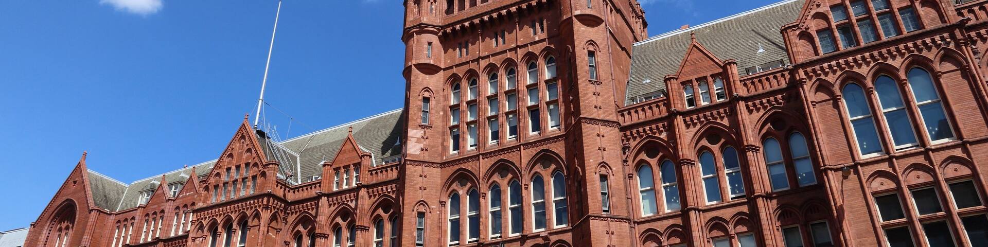 A large red brick building with multiple towers and arched windows.