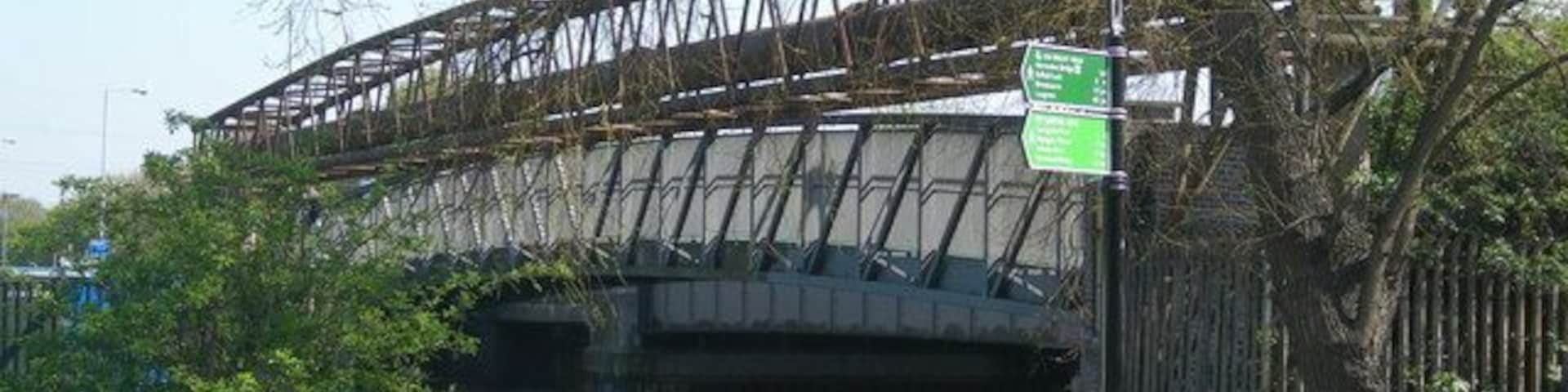 The Lea Bridge In fact, there are 2 bridges, one a footbridge (nearest) and also the road bridge. The green signs nearby refer to a London wide network of footpaths; the Capital Ring and the Lea Valley Walk. "I don't know what the large pipes in the foreground are for."