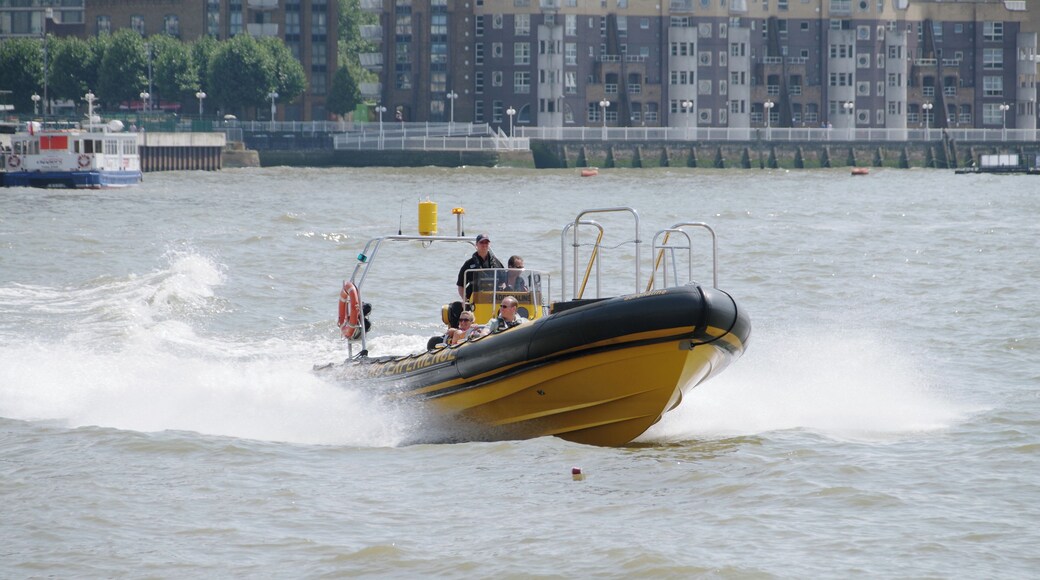 The Thames Rib Experience boat "Adrenaline" speeds along the Thames round the bend at Canary Wharf.