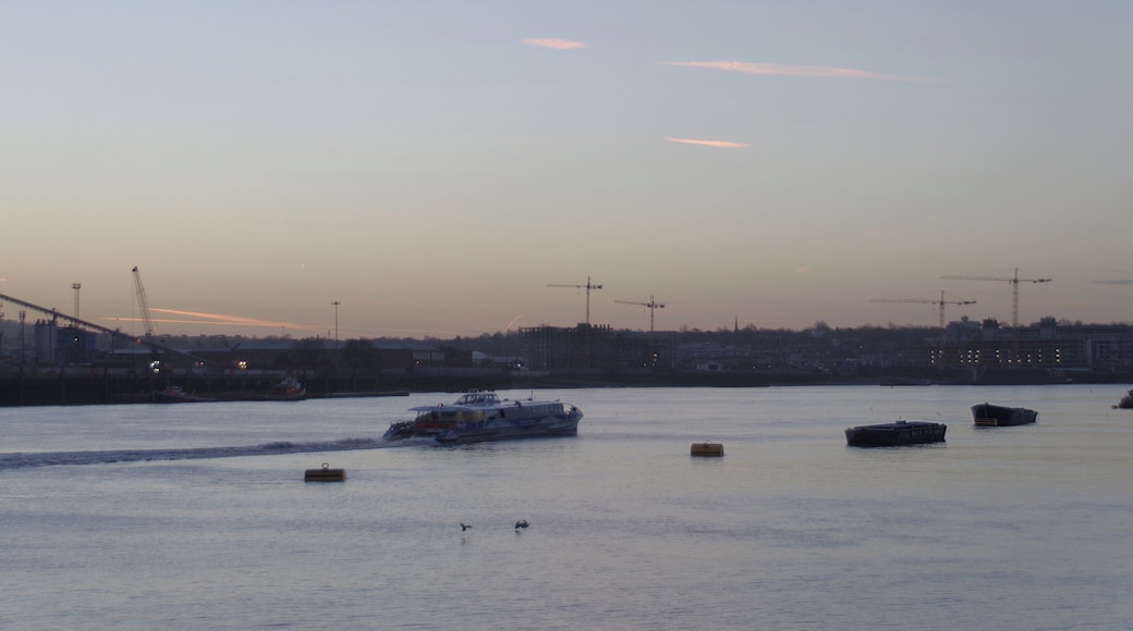 A Thames Clipper speeds west along the Thames, past Greenwich, just before sunrise. This was taken from near the eastern end of the City Canal.