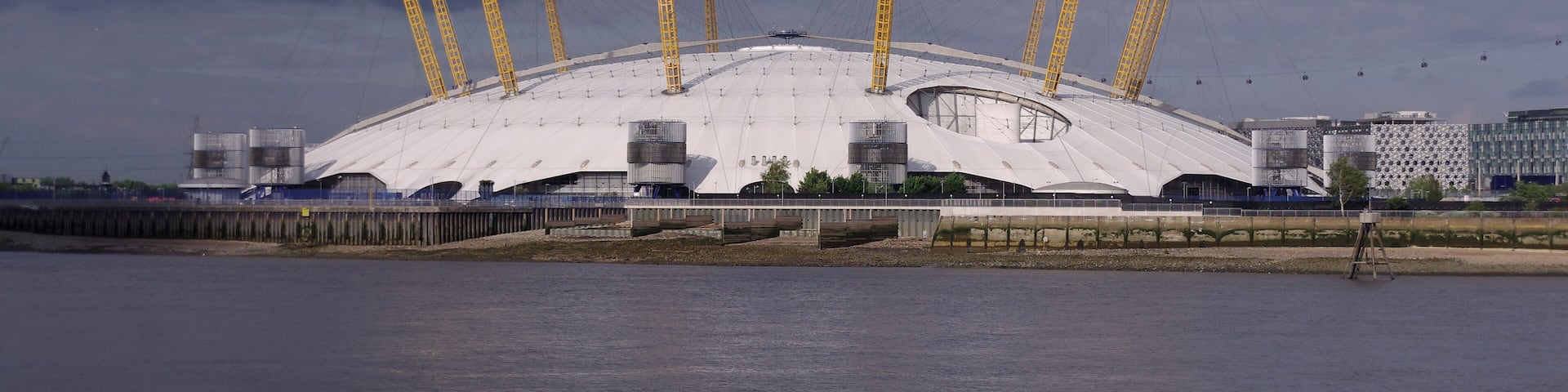 A large stadium with a white roof and yellow support structures.