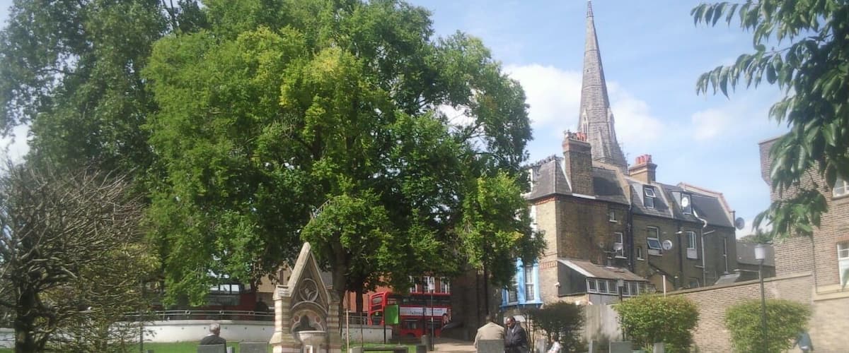 Part of Streatham Green, London SW16, looking north to the Dyce Drinking Fountain (left) and spire of the Roman Catholic church of the English Martyrs. The Dyce Fountain was moved here in 1933 from Streatham High Road.