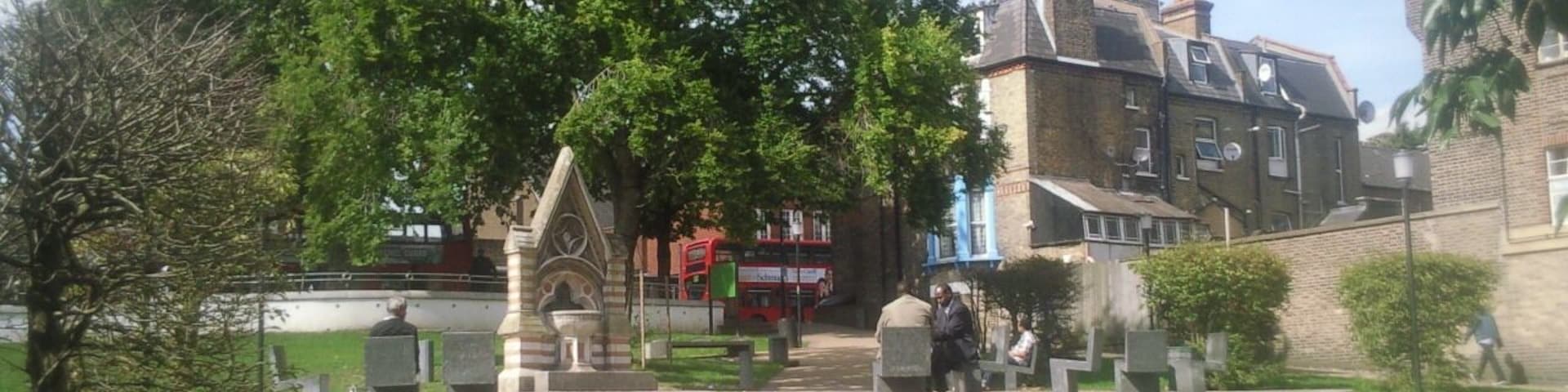 Part of Streatham Green, London SW16, looking north to the Dyce Drinking Fountain (left) and spire of the Roman Catholic church of the English Martyrs. The Dyce Fountain was moved here in 1933 from Streatham High Road.