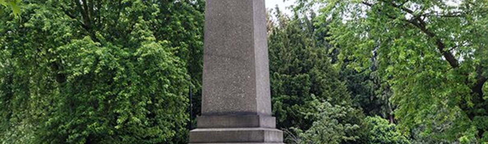 The "monument' in the image is a memorial drinking fountain. Erected in 1879, it originally stood in the middle of the road a little further to the south at the junction with Park Avenue. It was moved in 1904 to accommodate new tram routes. The main inscription on east face reads 'Erected in affectionate remembrance of Mrs Catherine Smithies of Earlham Grove, Wood Green, Founder of the Band of Mercy Movement, and presented by her family and friends for the use of the public'. The stone forming the obelisk is twenty-one feet in length. In 1879 it was the longest single cut stone in London, with the exception Cleopatra's Needle on the Thames Embankment. Made of polished granite, it was quarried from the Penryn quarries of Freeman and Sons, in Cornwall.