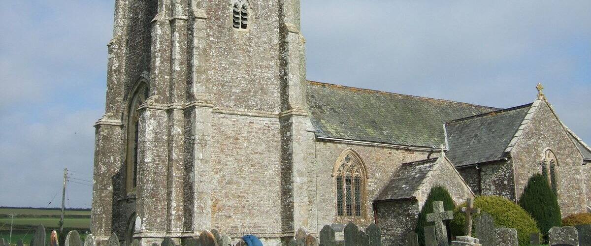 A historic church with a tall tower and a graveyard in front.