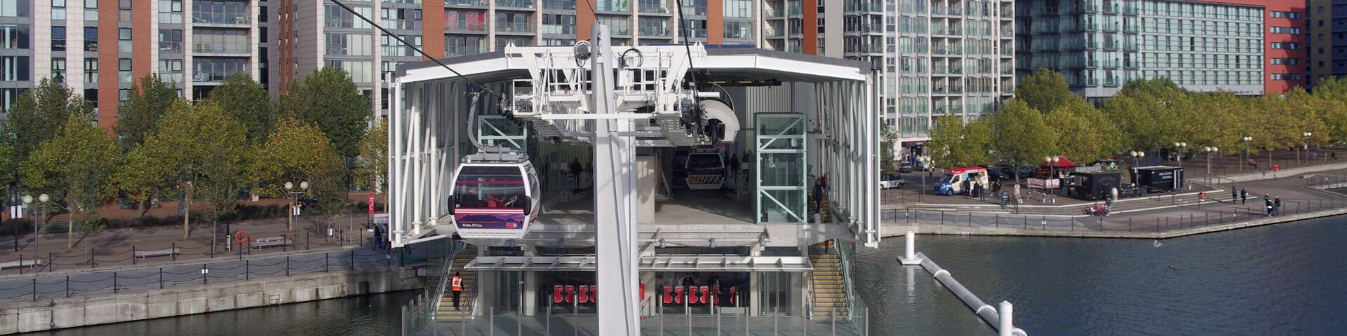A modern cable car system over a river with high-rise buildings in the background.