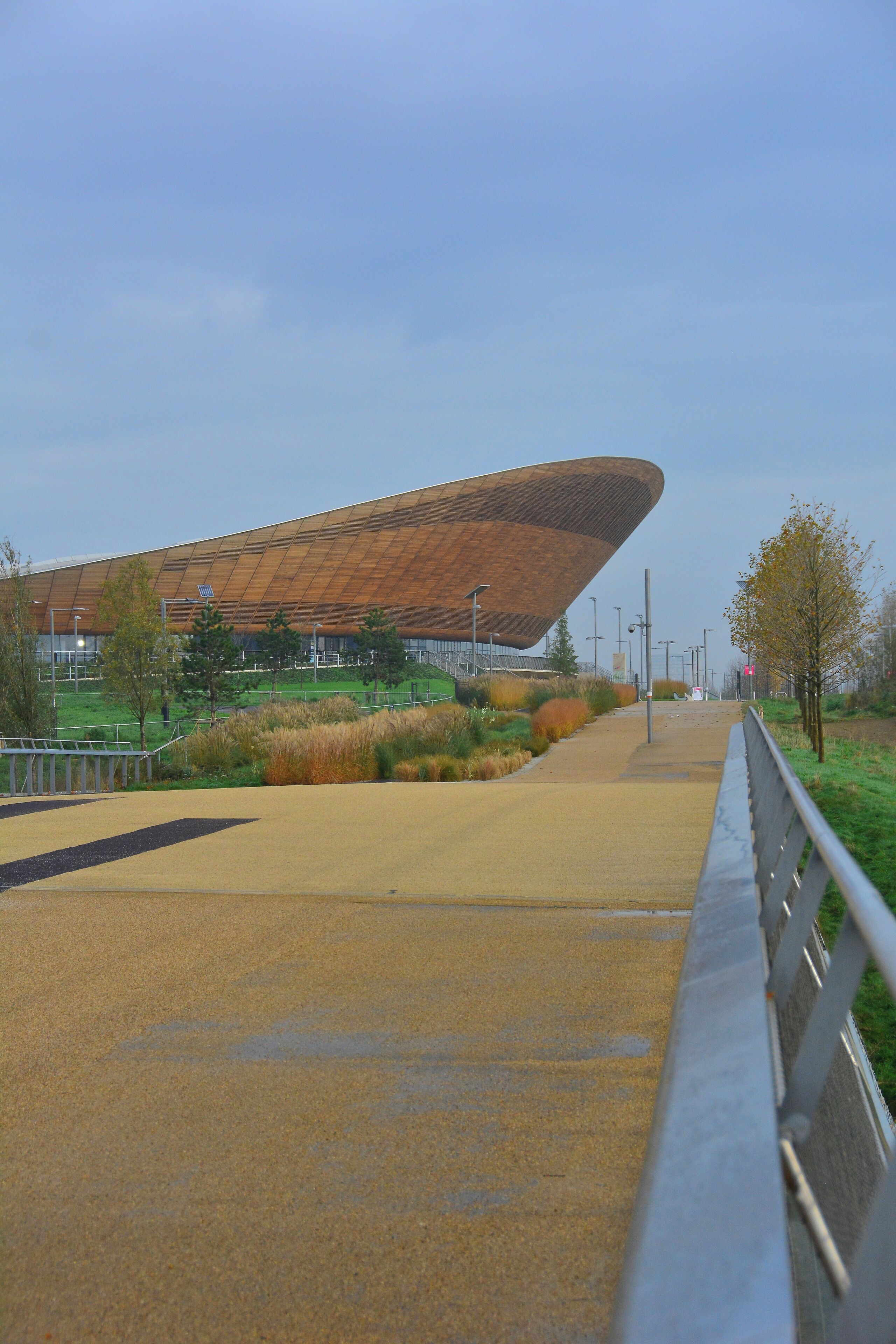 Ein modernes Stadion mit markanter, gewölbter Dachkonstruktion, umgeben von einer Grünanlage mit Bäumen und Rasen.