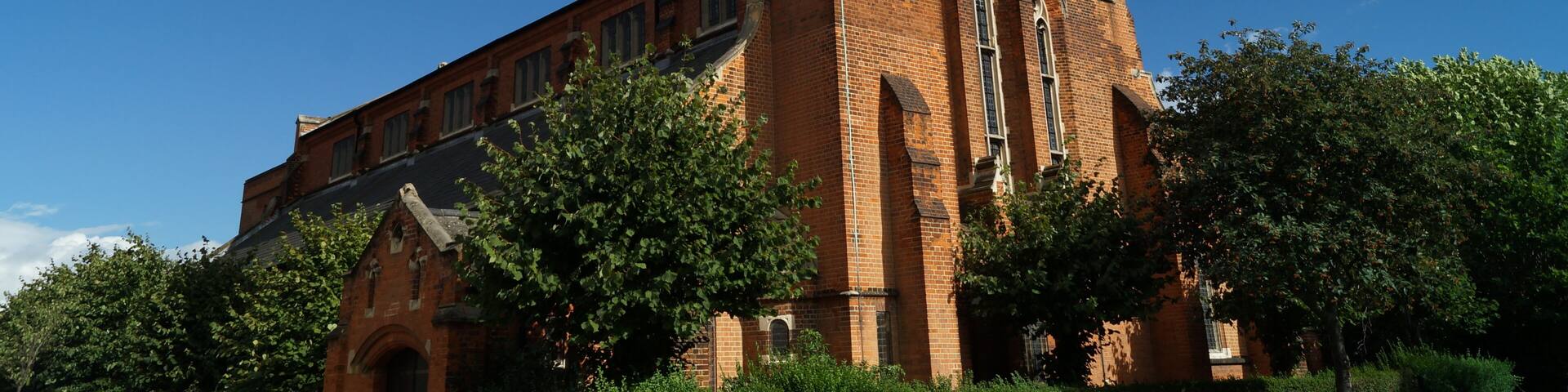 A large brick church with a tall tower and a weather vane.