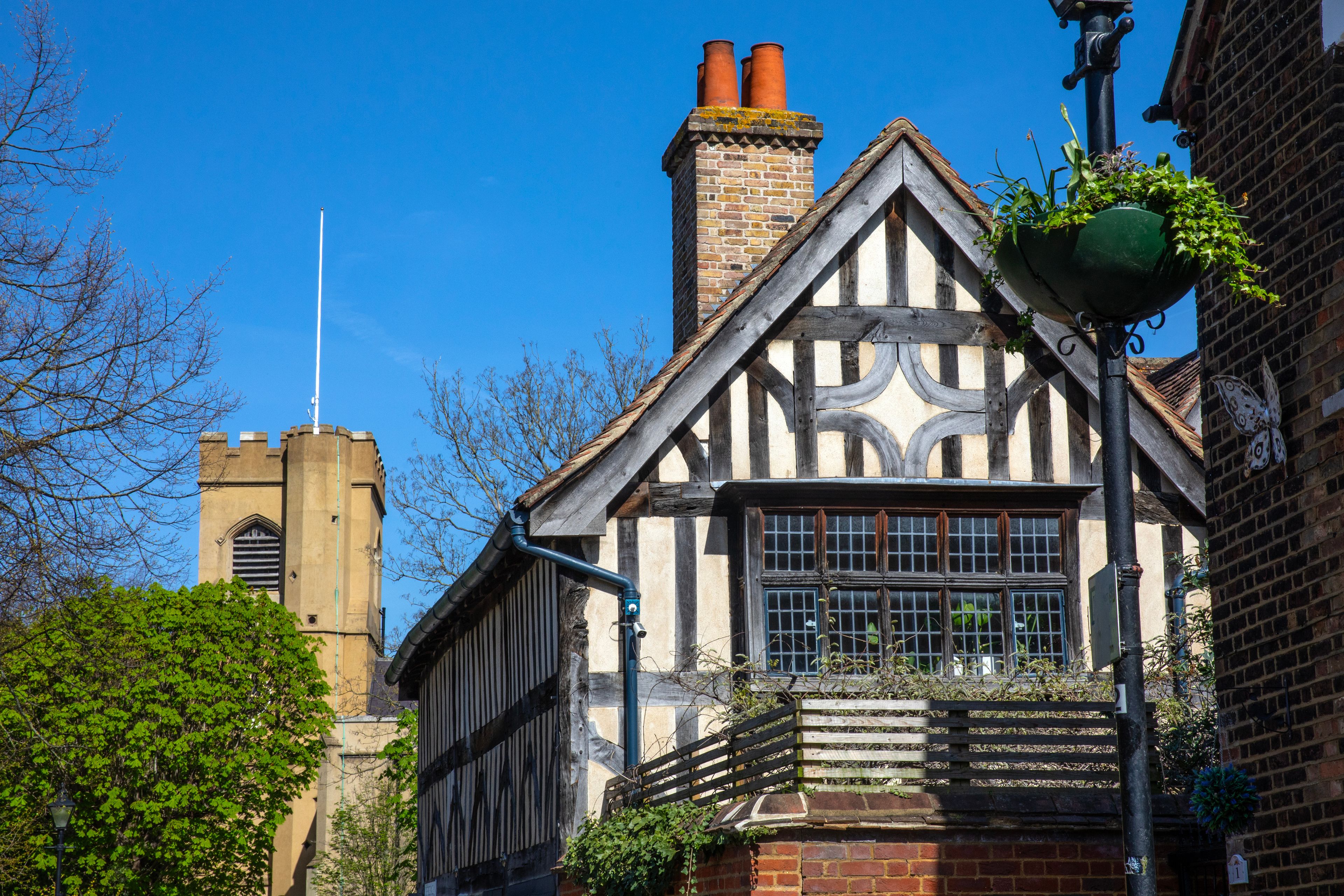 A Tudor-style building with a black and white timber frame, a brick chimney, and a traditional window design.