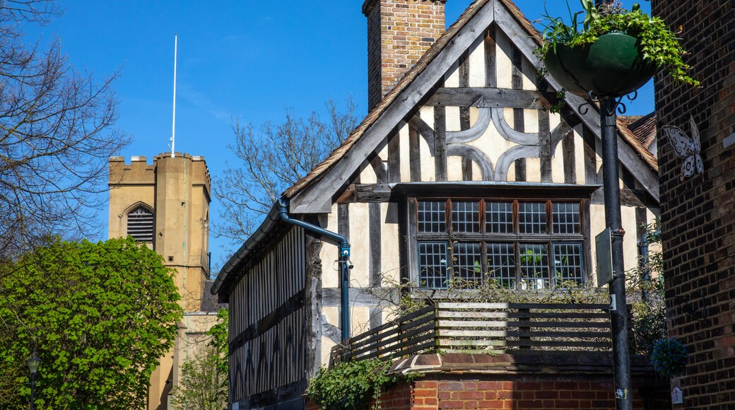 A Tudor-style building with a black and white timber frame, a brick chimney, and a traditional window design.