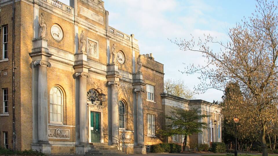 A historic building with classical architecture, featuring columns, arched windows, and detailed stonework.