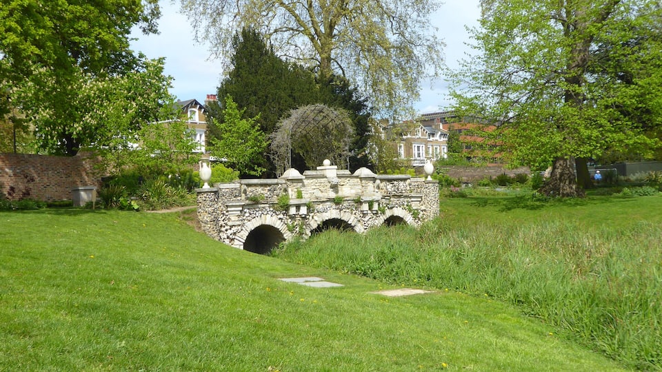Eine Steinkonstruktion mit Bögen in einem üppig grünen Park.