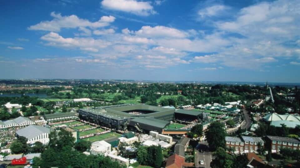 An aerial view of a city with a large stadium, historic buildings, and surrounding greenery.