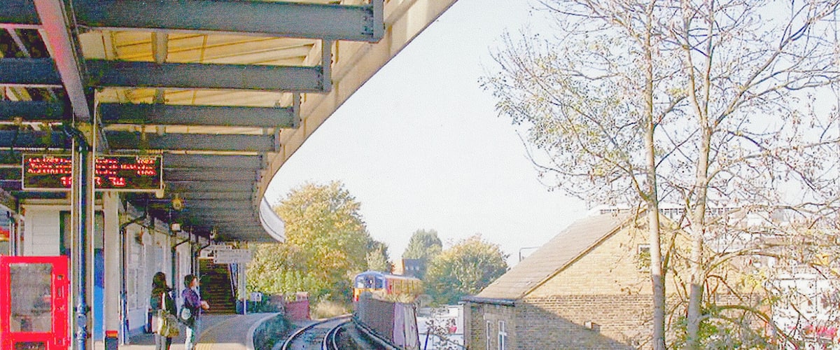 Raynes Park Station, Platform 1 2007. View westward, towards Motspur Park, Epsom etc., with Up local train for Waterloo arriving. The Up Epsom line, which comes from the south, burrows under the Down side and the main line to reach the Up platform.