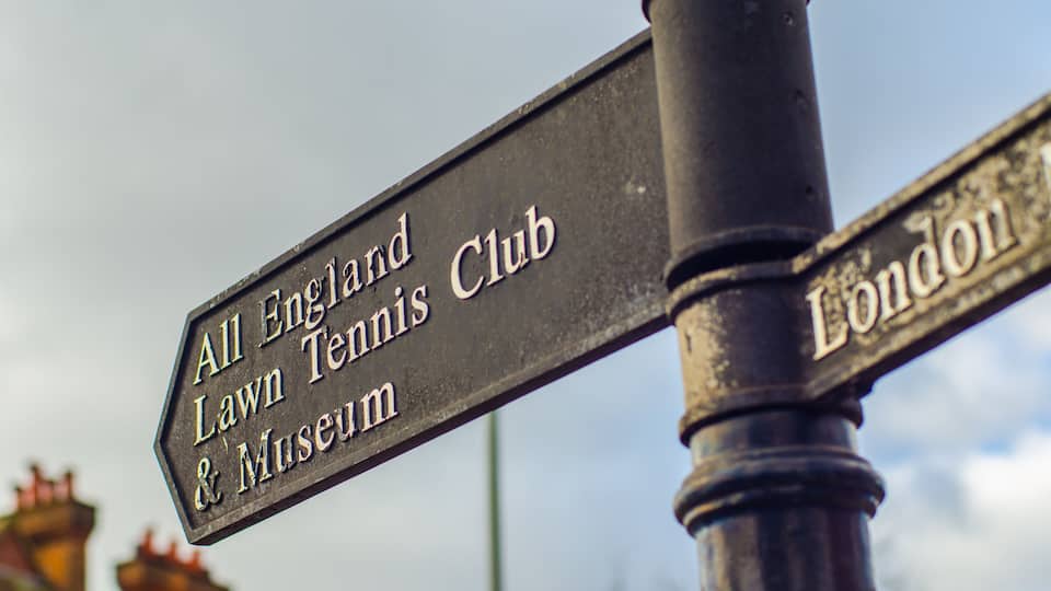 A directional signpost with 'All England Lawn Tennis Club & Museum' and 'London' directions.