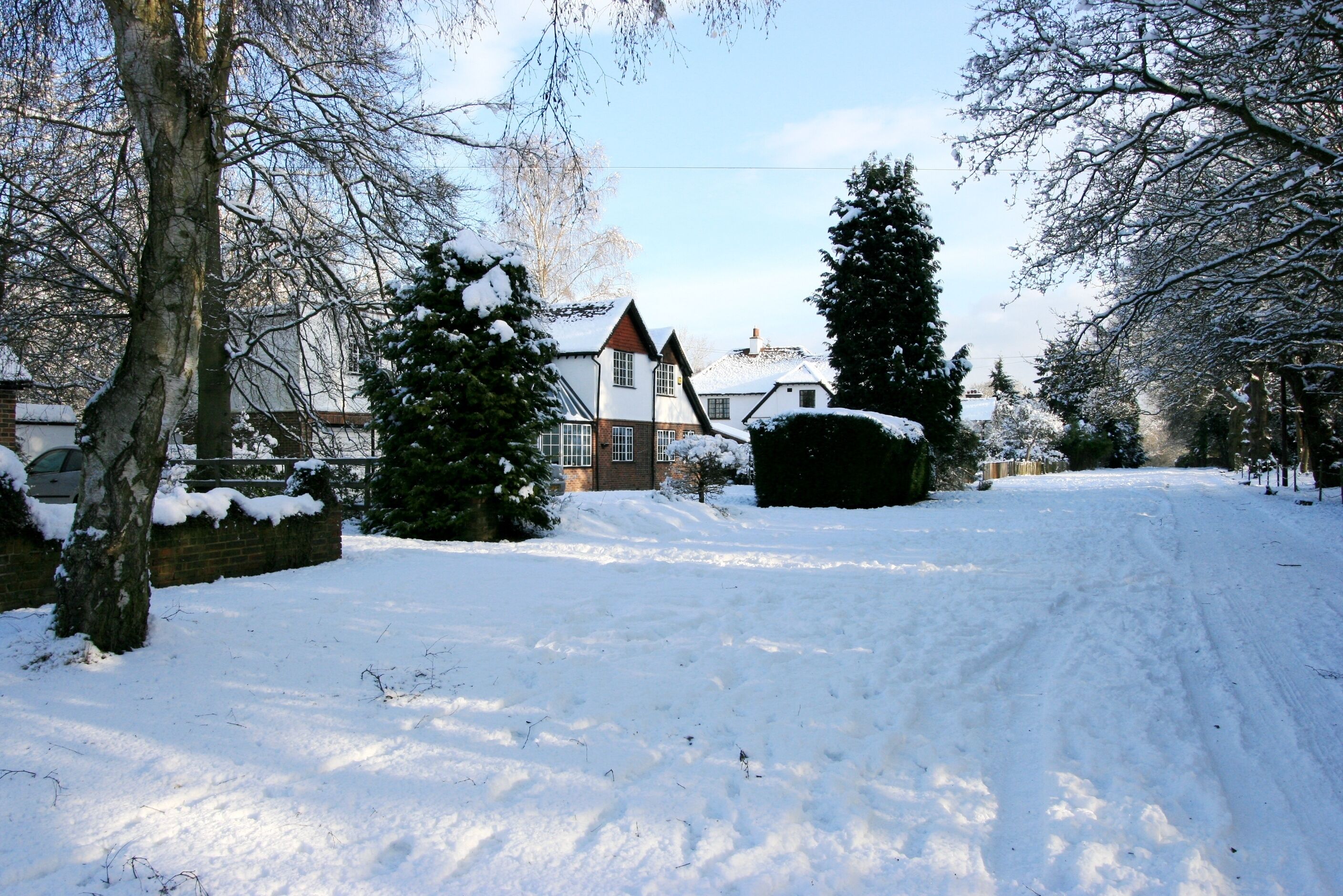 A snow-covered residential street with houses and trees.