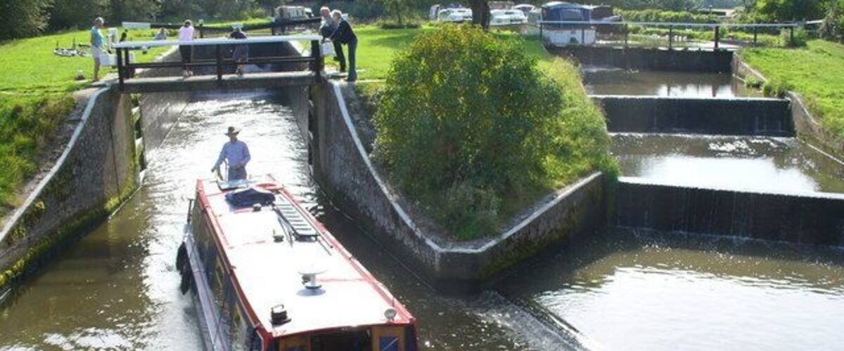 A narrow canal with a boat named 'Bella' passing through a lock system.