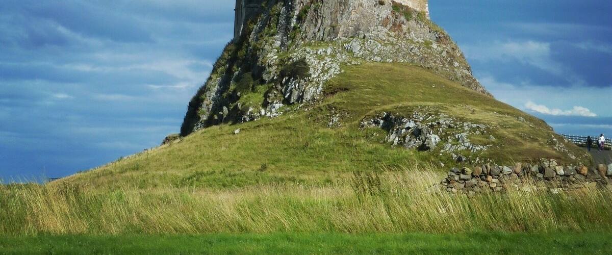 A castle on a grassy hill under a cloudy sky.
