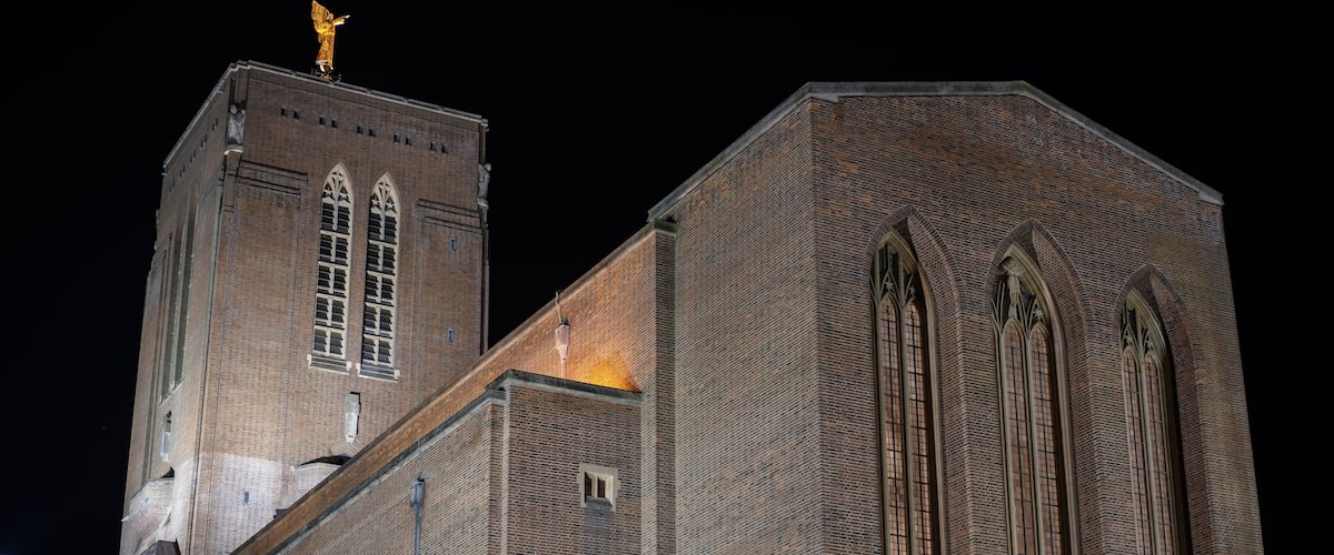 A large brick building with arched windows and a golden statue on top.