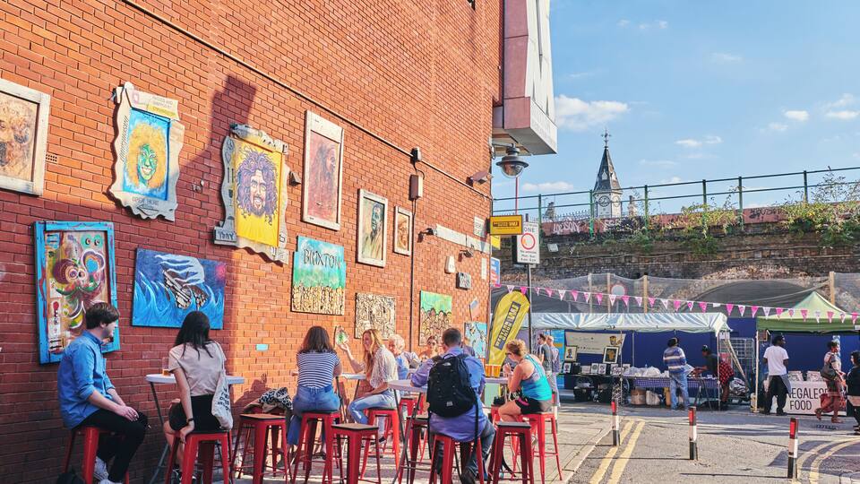 A brick building with colorful murals and red bar stools.