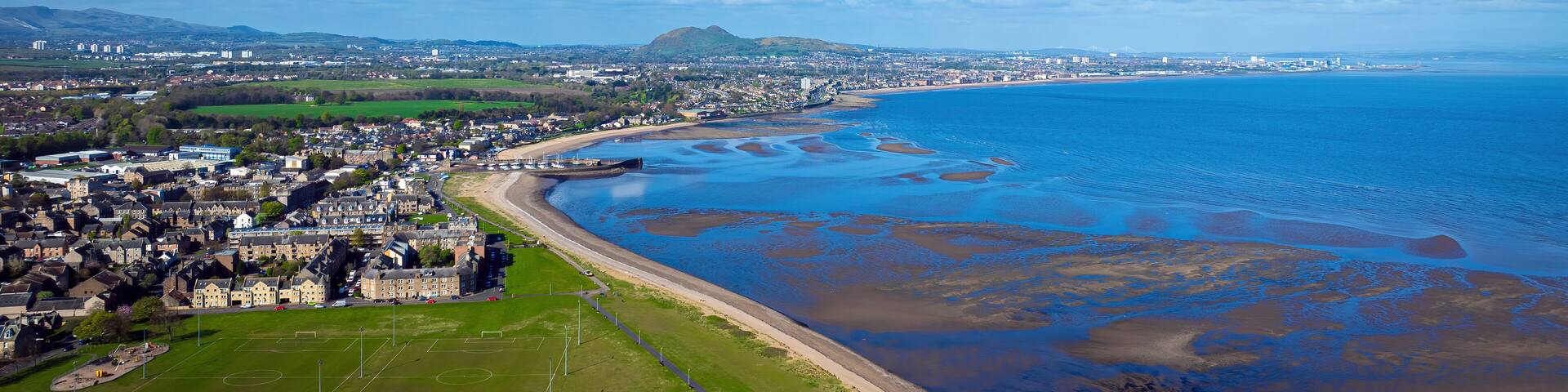 Aerial view of coastal village with ocean and mountains, Millhill, Musselburgh, Scotland.
