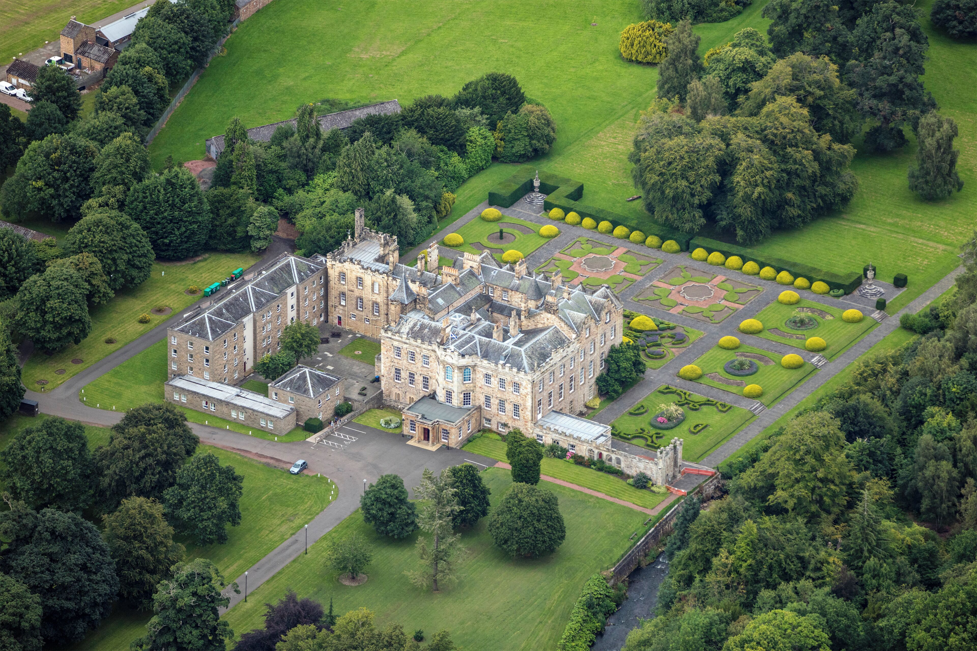 An aerial view of a historic castle surrounded by lush gardens and trees.