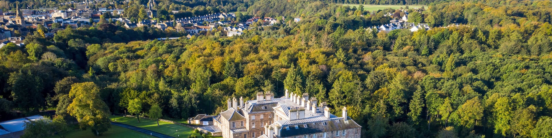 Aerial view of historic castle surrounded by forest in Dalkeith Country Park, Midlothian, Scotland.