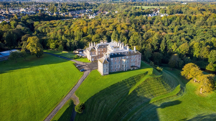 Aerial view of historic castle surrounded by forest in Dalkeith Country Park, Midlothian, Scotland.