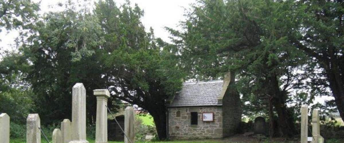 A cemetery with gravestones and a small stone building.