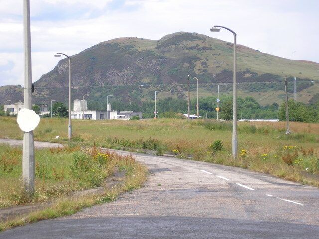 A street with no houses in Craigmillar The view of street where the houses have been demolished and have been replaced by grass and weeds. Arthur's Seat can be seen in the background.