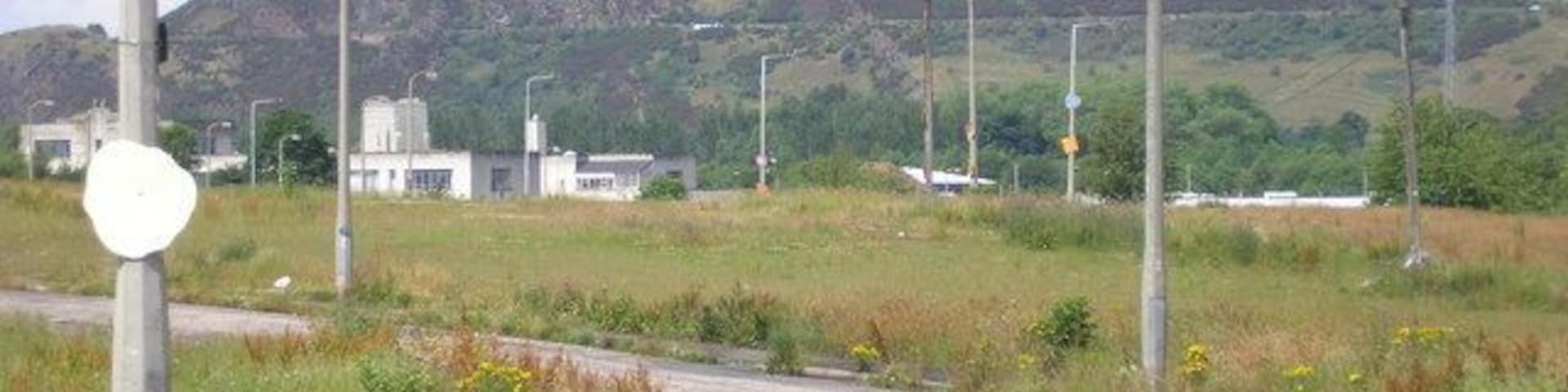 A street with no houses in Craigmillar The view of street where the houses have been demolished and have been replaced by grass and weeds. Arthur's Seat can be seen in the background.
